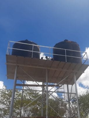 A couple of black water tanks on top of a wooden structure.