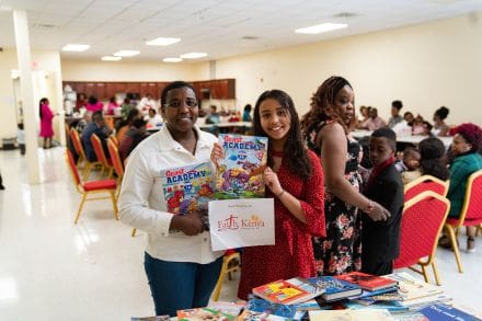 Two women holding a book and some boxes