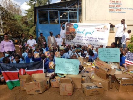 A group of people sitting around boxes in front of a building.