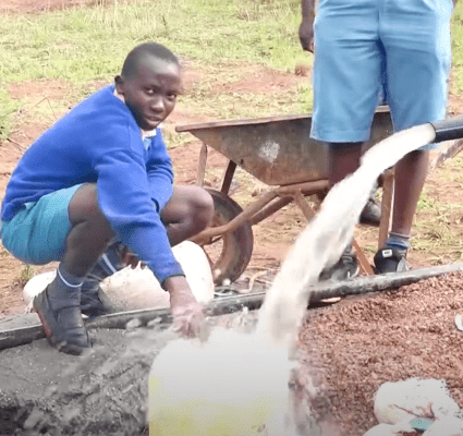 A boy is pouring water into the ground.