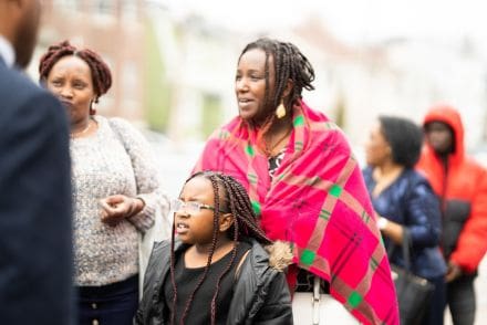 A woman in a red blanket standing next to two other women.