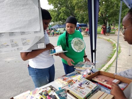 Two women looking at books on a table.