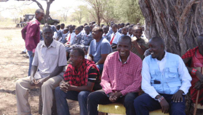 A group of people sitting in front of trees.