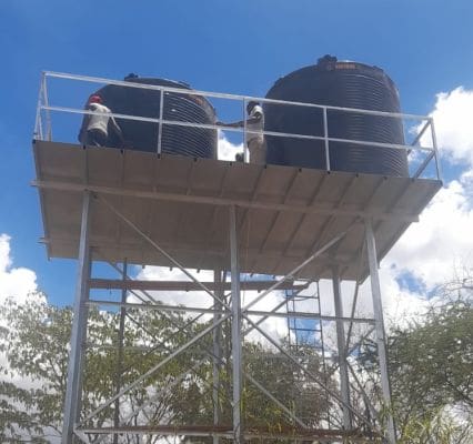 A couple of people on top of a metal structure.