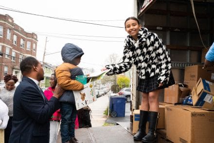 A woman handing something to a child.